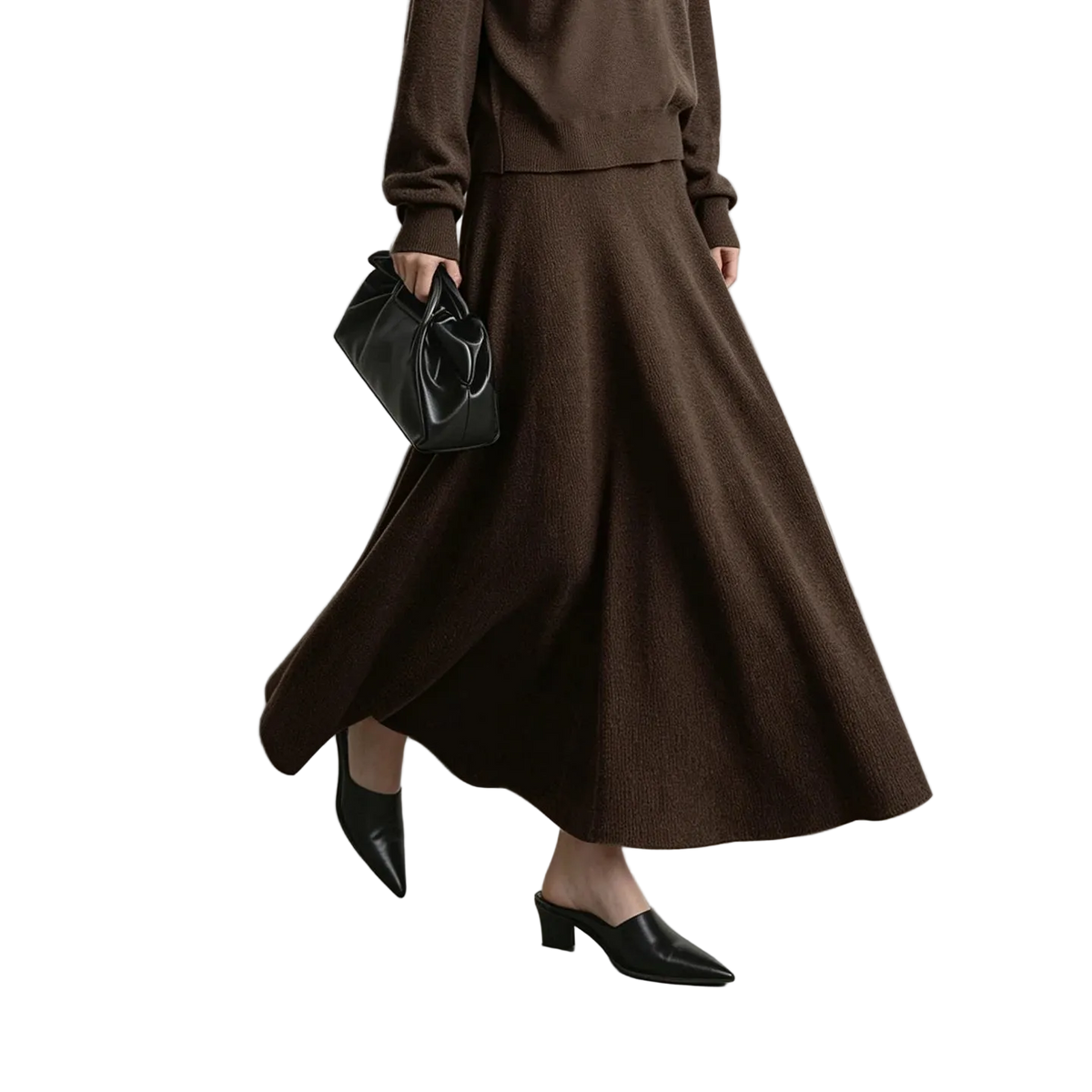 A model wearing a brown knit long-sleeve top and matching high-waisted A-line midi skirt, styled with black pointed-toe mule heels and a black leather handbag. The AMII brand logo is visible in the top left corner against a neutral gray studio background.