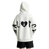 A person shown from the back wearing an oversized white hoodie with large black graphic lettering and a black heart containing the letter A on the back, paired with black shorts. The brand name AMII appears in the top left corner.