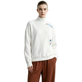 A model wearing an off-white AMII turtleneck sweatshirt with colorful embroidered logo details on the chest and waist, paired with brown drawstring pants, set against a plain light gray background.