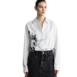 A model wearing a white long-sleeve button-up shirt with a black and gray abstract brushstroke print on the front, paired with a dark denim skirt. The brand name 'AMII' is visible in the top left corner.