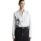 A model wearing a white long-sleeve button-up shirt with a black and gray abstract brushstroke print on the front, paired with a dark denim skirt. The brand name 'AMII' is visible in the top left corner.