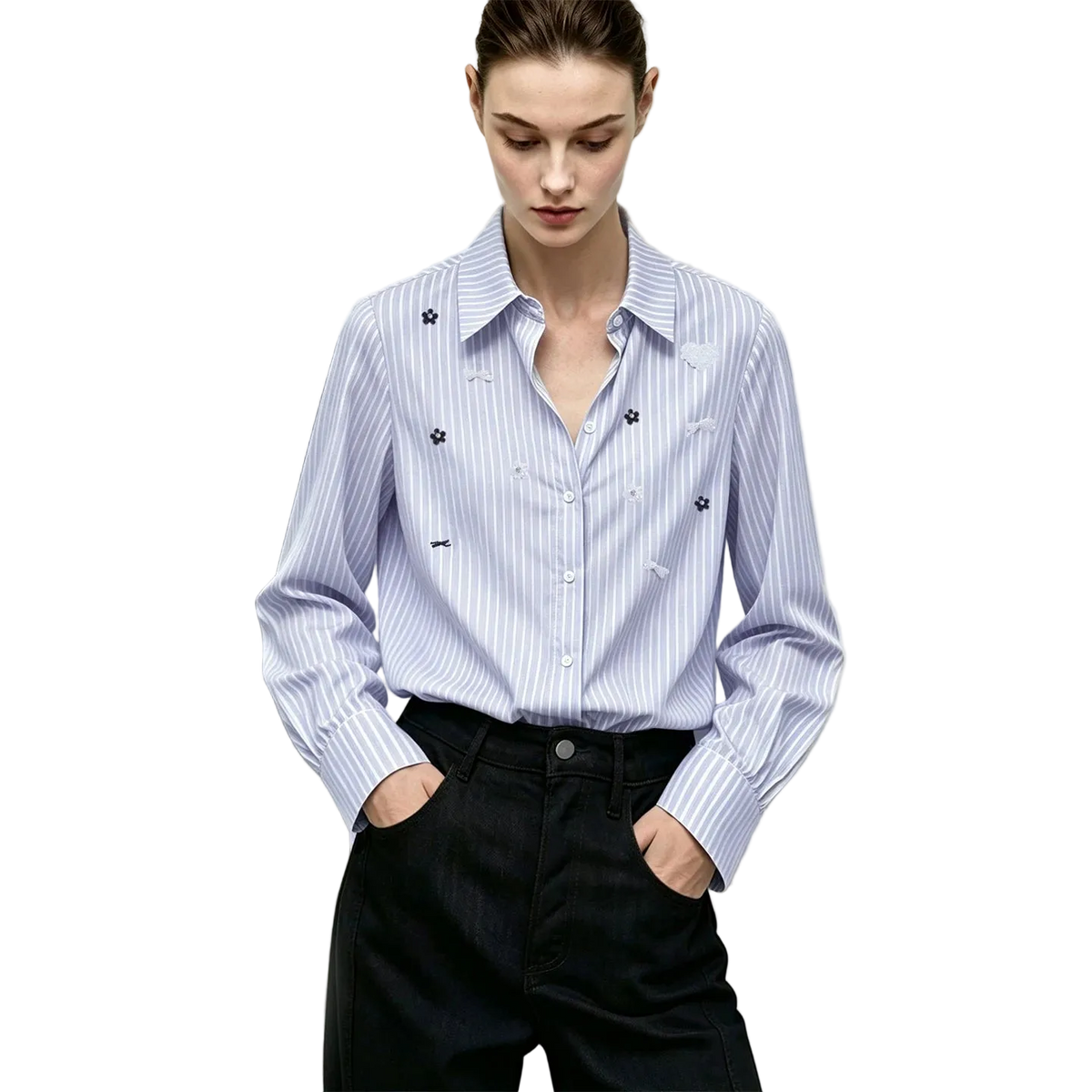 A woman wearing a light blue and white vertically striped long-sleeve button-up shirt with small embroidered floral details on the chest, paired with dark trousers. The AMII brand logo is visible in the top left corner.