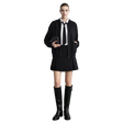 A model stands against a light gray wall wearing a black zip-front jacket over a white collared shirt with a black tie, a black pleated mini skirt, and tall black knee-high boots.