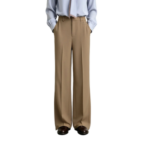 A model from the waist down wearing AMII wide-leg trousers in a light tan color, paired with a light blue button-down shirt and dark brown leather shoes, set against a plain light gray studio background.