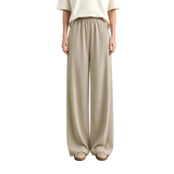 A model from the waist down wearing AMII wide-leg trousers in a light beige color, paired with a cream top and beige shoes, standing against a neutral studio background.