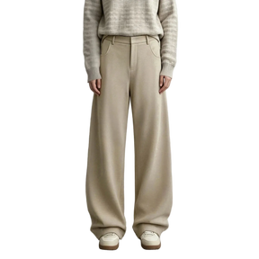 A model wearing AMII wide-leg knit trousers in a light beige color, paired with a textured beige sweater and cream shoes, standing against a neutral gray studio background.
