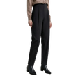 A model wearing black high-waisted, straight-leg trousers with pleats, paired with a beige sweater and black pointed-toe ankle boots. The AMII brand logo is visible in the top-left corner against a neutral light gray studio background.