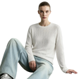 A model wearing a cream cable-knit long-sleeve sweater and light-wash wide-leg jeans, sitting against a light gray wall. The brand name 'AMII' is printed in black in the top-left corner.