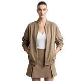 A model wearing a taupe brown bomber jacket, matching pleated mini skirt, and a white top, standing against a light gray background with the AMII logo in the top left corner.