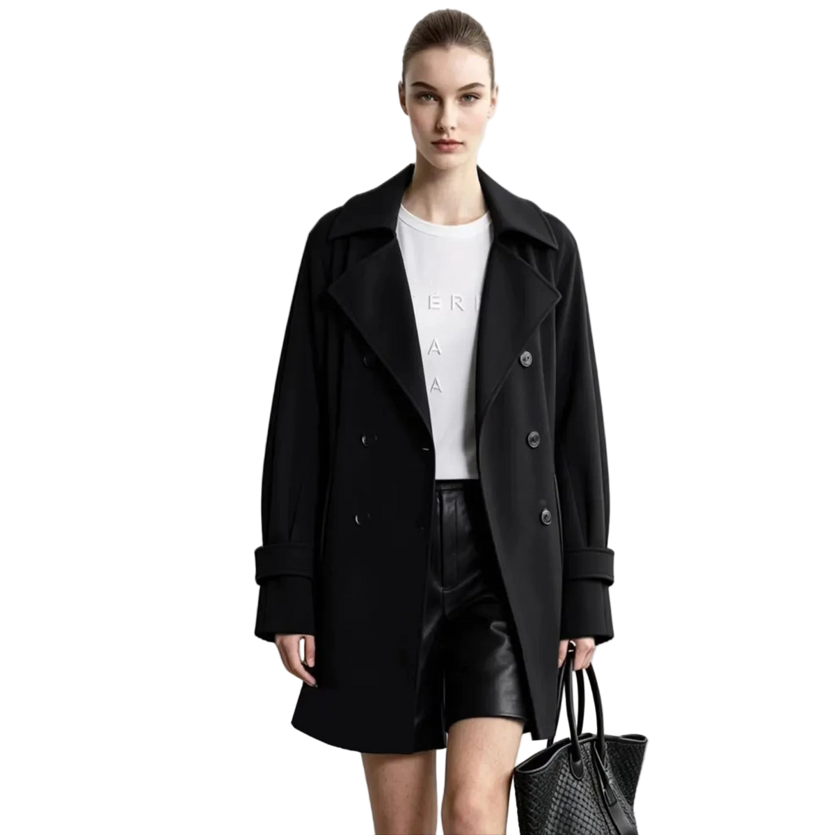 A model wearing a black double-breasted AMII coat over a white top and black shorts, holding a black textured handbag against a light gray studio background. An informational graphic on the left highlights the wrinkle-resistant, no-iron fabric.