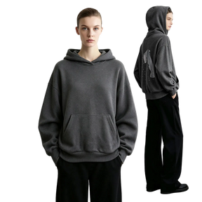 A model wears a dark gray AMII pullover hoodie with a kangaroo pocket, shown from the front and back against a minimalist light gray studio background.