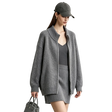A woman modeling an AMII oversized zip-up cardigan in heather gray, paired with a matching gray knit mini skirt and a dark gray baseball cap, holding a gray handbag against a light gray studio background.