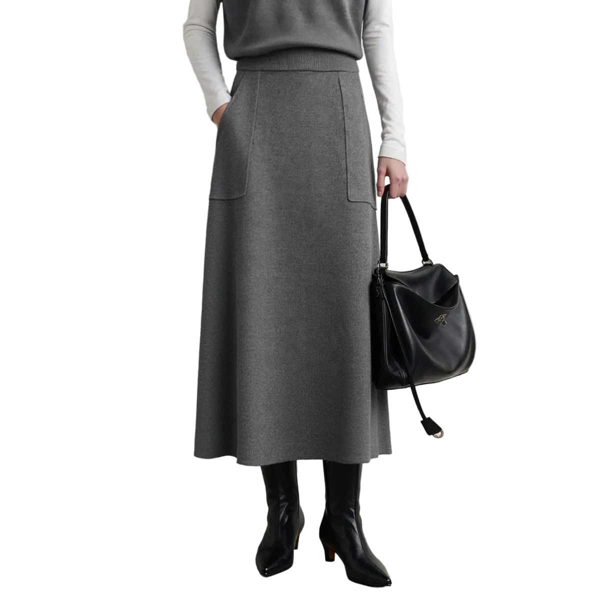 A model wearing a gray A-line midi skirt with two front patch pockets, styled with a gray top, white long-sleeve shirt, black ankle boots, and holding a black leather shoulder bag. The AMII brand logo is visible in the top left corner.