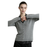 A woman modeling a light gray ribbed cardigan sweater with a V-neck and button front, layered over a black collared shirt. The brand name AMII is printed in black in the top left corner against a light gray background.