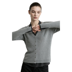 A woman modeling a light gray ribbed cardigan sweater with a V-neck and button front, layered over a black collared shirt. The brand name AMII is printed in black in the top left corner against a light gray background.