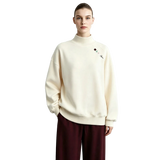 A model wearing an AMII cream-colored mock-neck sweatshirt with a small embroidered logo on the left chest, paired with dark burgundy pants, set against a light gray studio background.