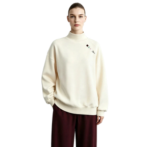 A model wearing an AMII cream-colored mock-neck sweatshirt with a small embroidered logo on the left chest, paired with dark burgundy pants, set against a light gray studio background.